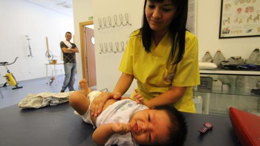 La fisioterapeuta Silvia Vela aplica un tratamiento a un bebe en el Centro de Rehabilitación Atlas.