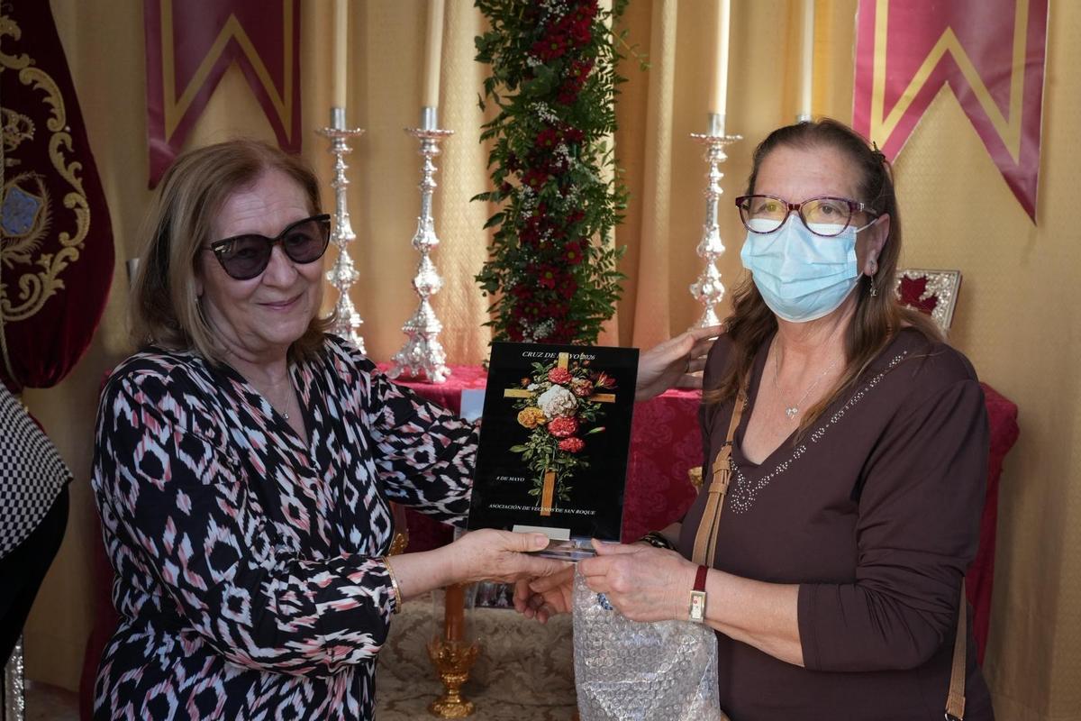 Marisol Sánchez, miembro de la cofradía de San Roque de Badajoz, recibe una placa conmemorativa de manos de la asociación de vecinos.