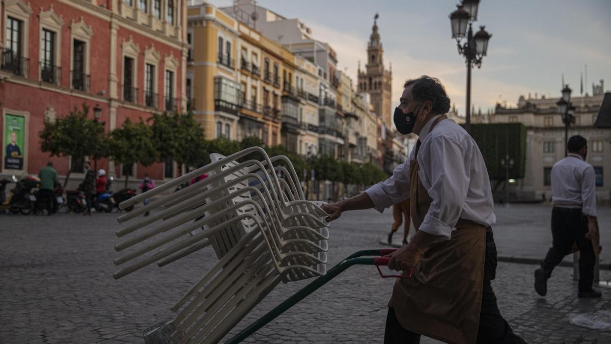 Un camarero recoge una terraza antes del toque de queda en Sevilla.