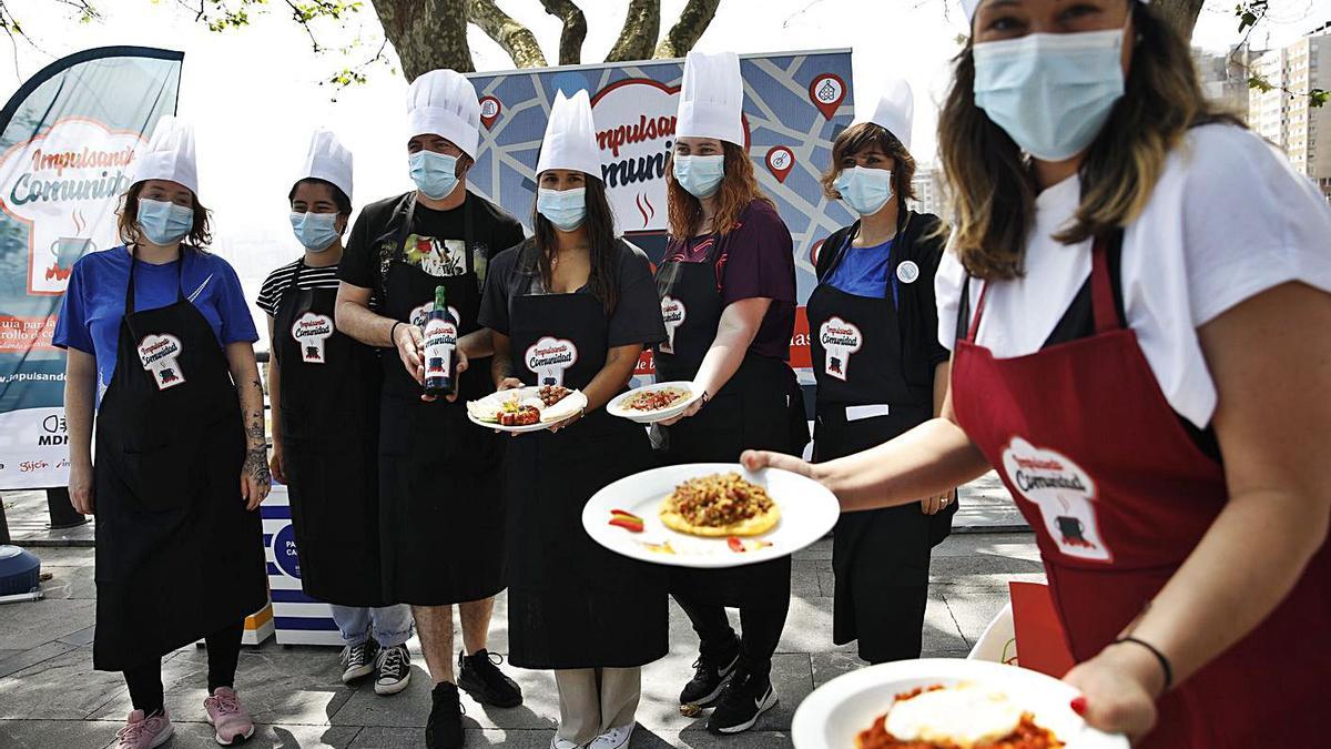 Los vecinos de El Llano y El Coto, en el Campo Valdés, en la preparación de los platos de comida para simbolizar las cocinas comunitarias dentro del proyecto “Impulsando comunidad” de Mar de Niebla.