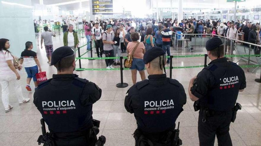 Agentes de la Policía autonómica catalana controlan los accesos a las puertas de embarque del aeropuerto barcelonés de El Prat.