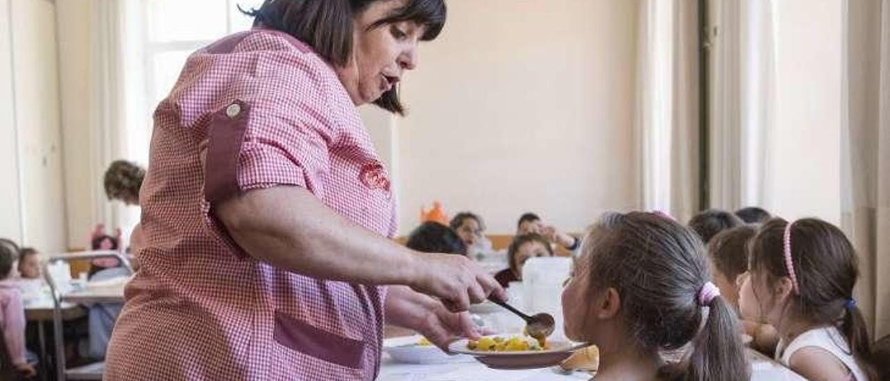 Una mujer atiende a una niña en un comedor escolar.