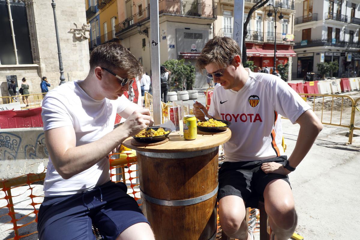 Dos turistas disfrutan de dos raciones de paella en la plaza del Mercado.