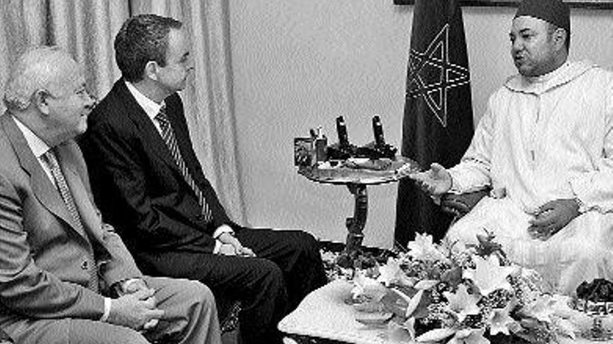 Mohamed VI conversa con Zapatero, que está acompañado por el ministro Moratinos. / chema moya