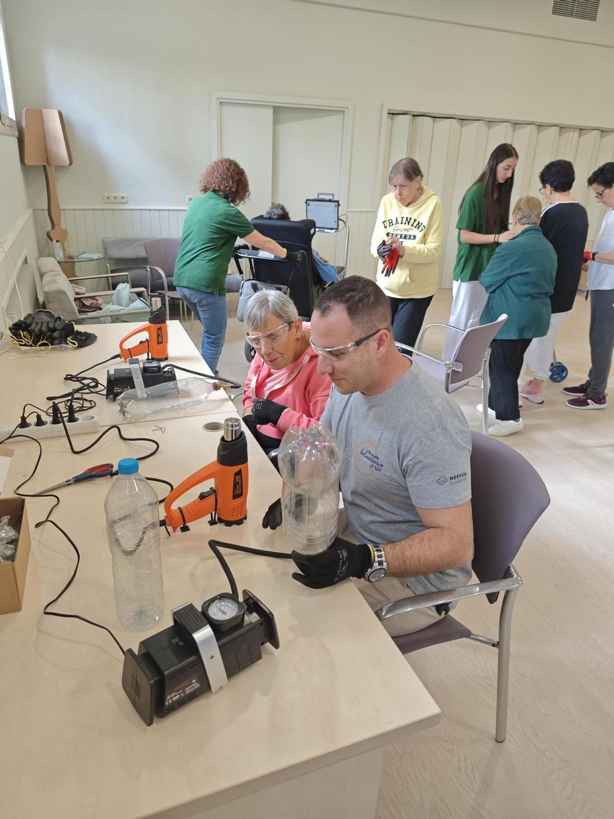 Voluntaris de Repsol mostrant a les residents del Centre Sant Josep com convertir les ampolles en filament 3D