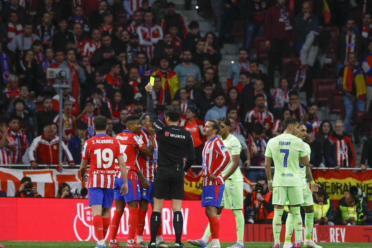 MADRID, 02/04/2025.- El colegiado Munuera Montero muestra tarjeta amarilla a Reinildo Mandava (2i), del Atlético de Madrid, durante el encuentro correspondiente a la vuelta de las semifinales de la Copa del Rey que Atlético de Madrid y FC Barcelona disputan hoy miércoles en el estadio Metropolitano. EFE/Juanjo Martín. atletico madrid . barça. copa del rey 2024/2025 atletico madrid . barça. semifinal vuelta. accion camiseta verde. riyadh air metropolitano