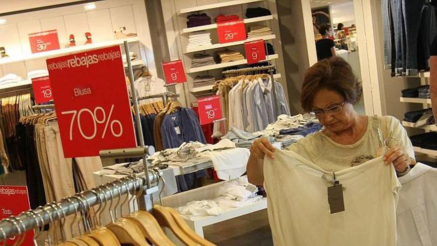 Una clienta observa una blusa en una tienda con descuentos del 70%.