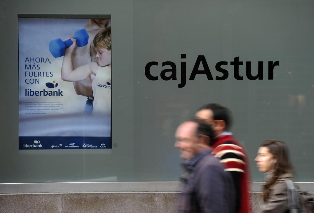 People walk past the Cajastur headquarters, part of Liberbank, in Oviedo, December 20, 2012. Spain’s Liberbank on Thursday said it planned a stock listing in the first half of 2013 as part of its recapitalisation plan. The announcement came after the European Commission approved the second phase of Spain’s banking sector overhaul. Liberbank will receive a temporary aid of 124 million euros in contingent convertible bonds, also know as Cocos. REUTERS/Eloy Alonso (SPAIN - Tags: BUSINESS)