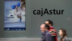 People walk past the Cajastur headquarters, part of Liberbank, in Oviedo, December 20, 2012. Spain’s Liberbank on Thursday said it planned a stock listing in the first half of 2013 as part of its recapitalisation plan. The announcement came after the European Commission approved the second phase of Spain’s banking sector overhaul. Liberbank will receive a temporary aid of 124 million euros in contingent convertible bonds, also know as Cocos. REUTERS/Eloy Alonso (SPAIN - Tags: BUSINESS)