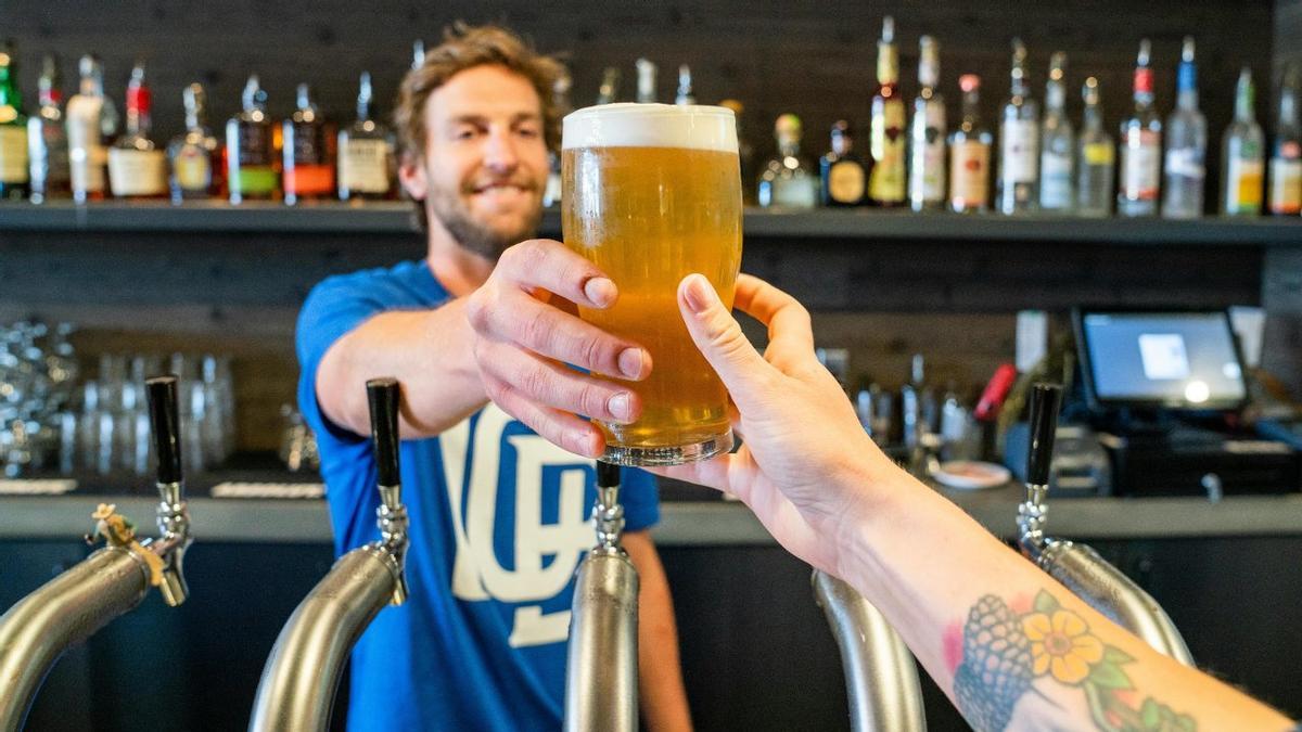 Un hombre sierve una cerveza a otra persona.