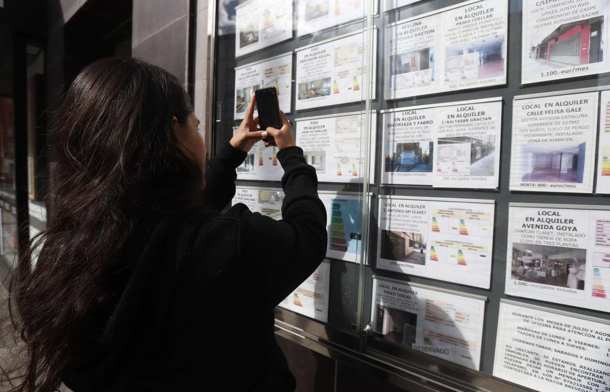 Una joven fotografía una oferta, en una inmobiliaria de Zaragoza.