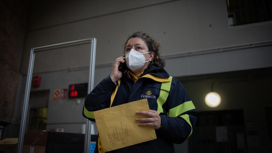 Una trabajadora de Correos deja los votos por correo mientras habla por teléfono en una mesa electoral.