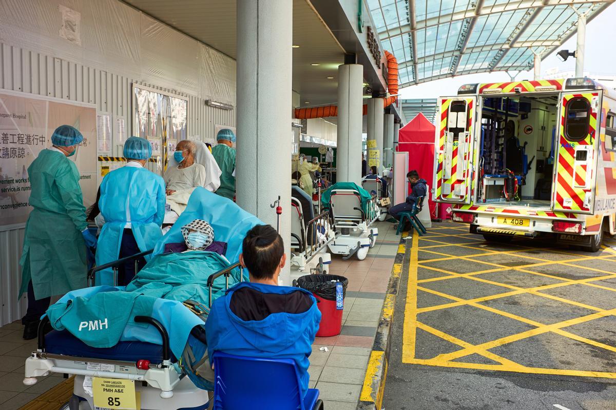 El personal del hospital transfiere pacientes de una ambulancia al departamento de emergencias del Hospital Princess Margaret en Hong Kong, ya que la ciudad enfrenta su peor brote de coronavirus en dos años.