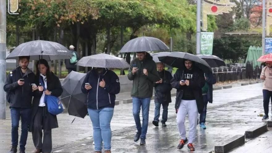 Personas paseando con paraguas, ayer, en Vigo. |  Alba Villar