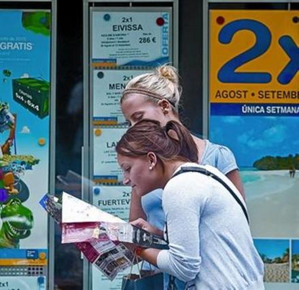 Dues turistes passen davant d’un comerç de Barcelona el mes passat.