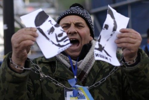 A protester with chained hands tears a portrait of Ukraine's President Viktor Yanukovich during a demonstration in Kiev