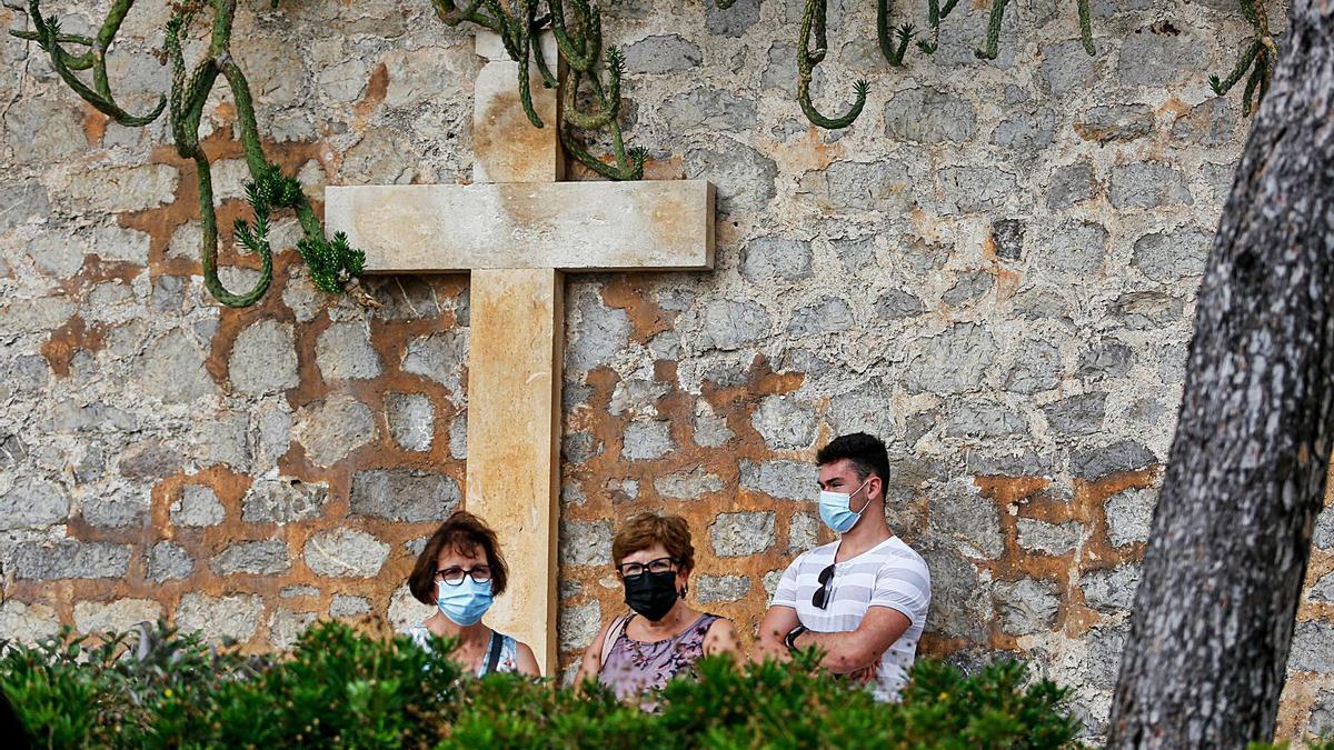  Tres personas contemplan la ofrenda a Guillem de Montgrí desde detrás de las vallas.