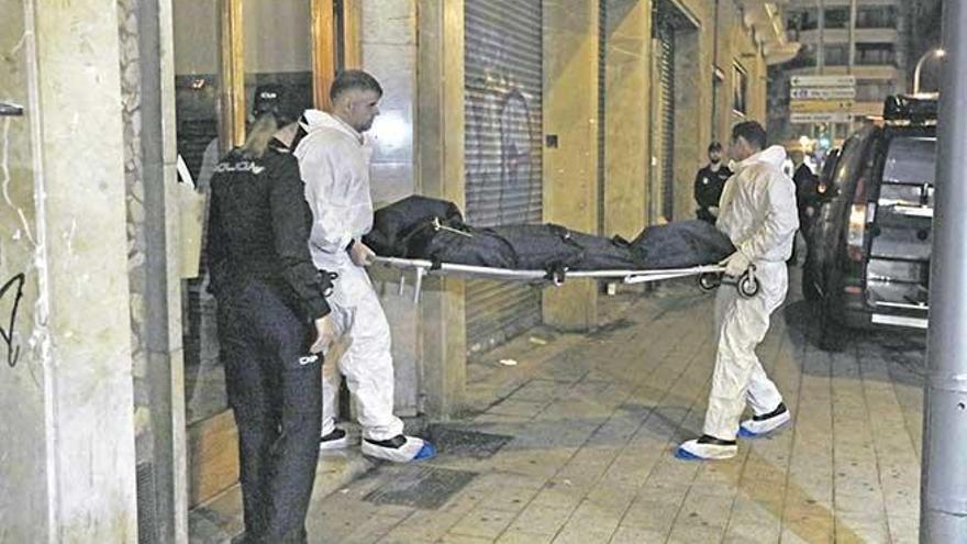 Operarios de los servicios funerarios trasladan uno de los cuerpos, el viernes, en el domicilio de la calle Gabriel Maura.