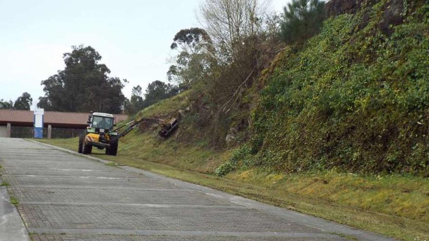 Un tractor acomete desbroces en un talud interior de la Feira Internacional de Galicia.