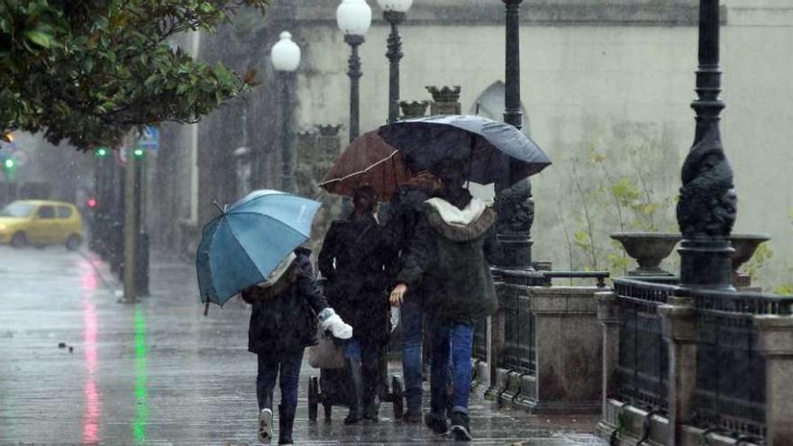 Un grupo de transeúntes se protege de la lluvia durante el última temporal de la ciudad. // R. Grobas