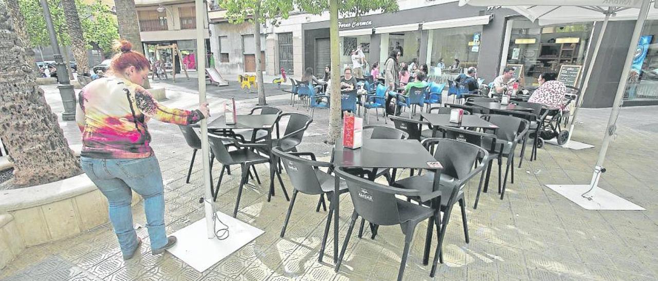 Una trabajadora de un establecimiento trata de acoplar sus mesas y sillas al espacio delimitado con marcas en el suelo
