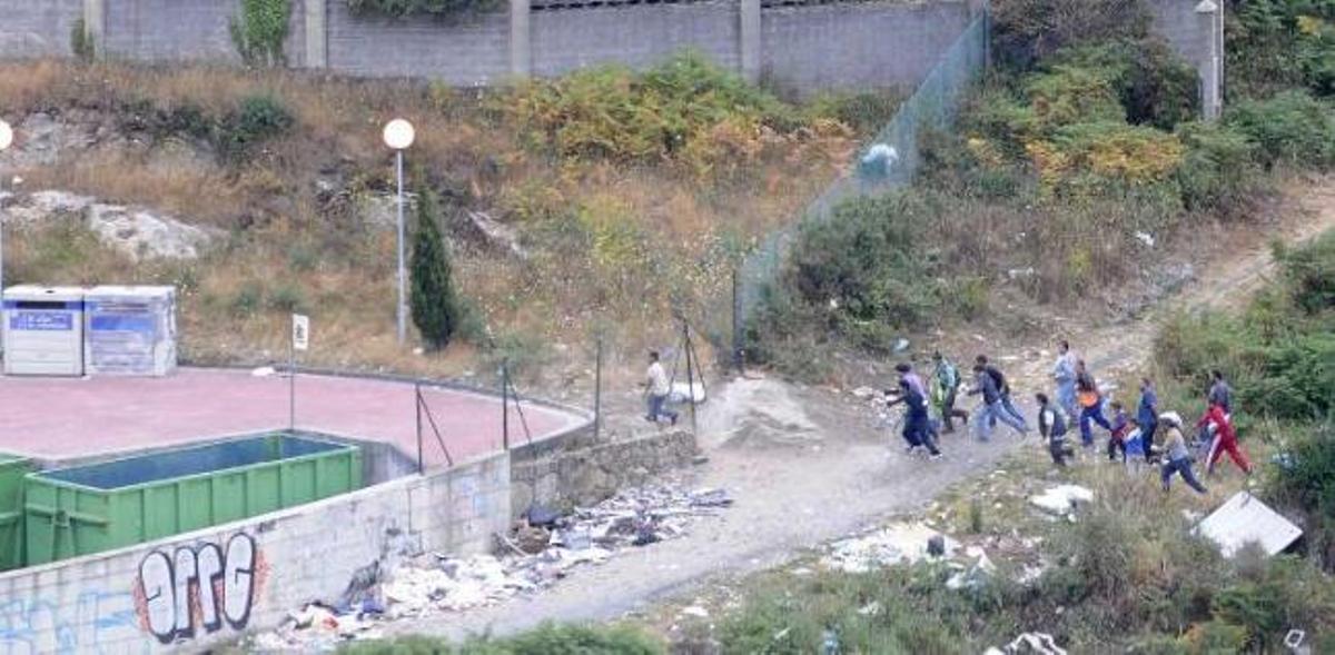 Arriba a la izquierda, el grupo de asaltantes sale de la zona de arbustos y entra por un hueco del alambrado; a la derecha, parte de la banda salta al interior de un contenedor; abajo izquierda, varios jóvenes extraen una lavadora mientras otros desmontan más electrodomésticos; abajo a la derecha, la banda barre la zona y carga lo sustraído en dos vehículos. / l. o.