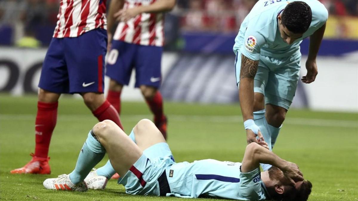 Suárez atiende a Messi, tumbado en el césped del Wanda