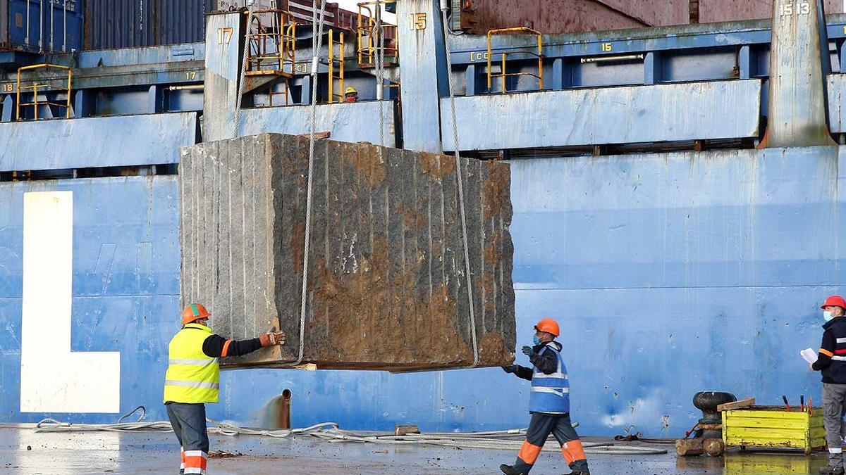 Operarios en el muelle transversal del Puerto, maniobrando con bloques de granito para la estiba