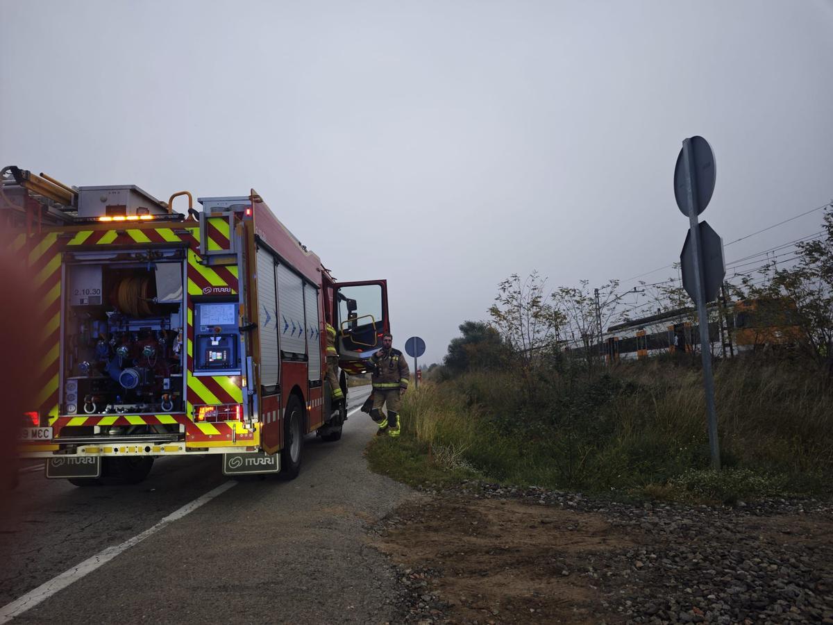 Un camió de bombers al costat de la via del tren, on hi ha el comboi aturat.