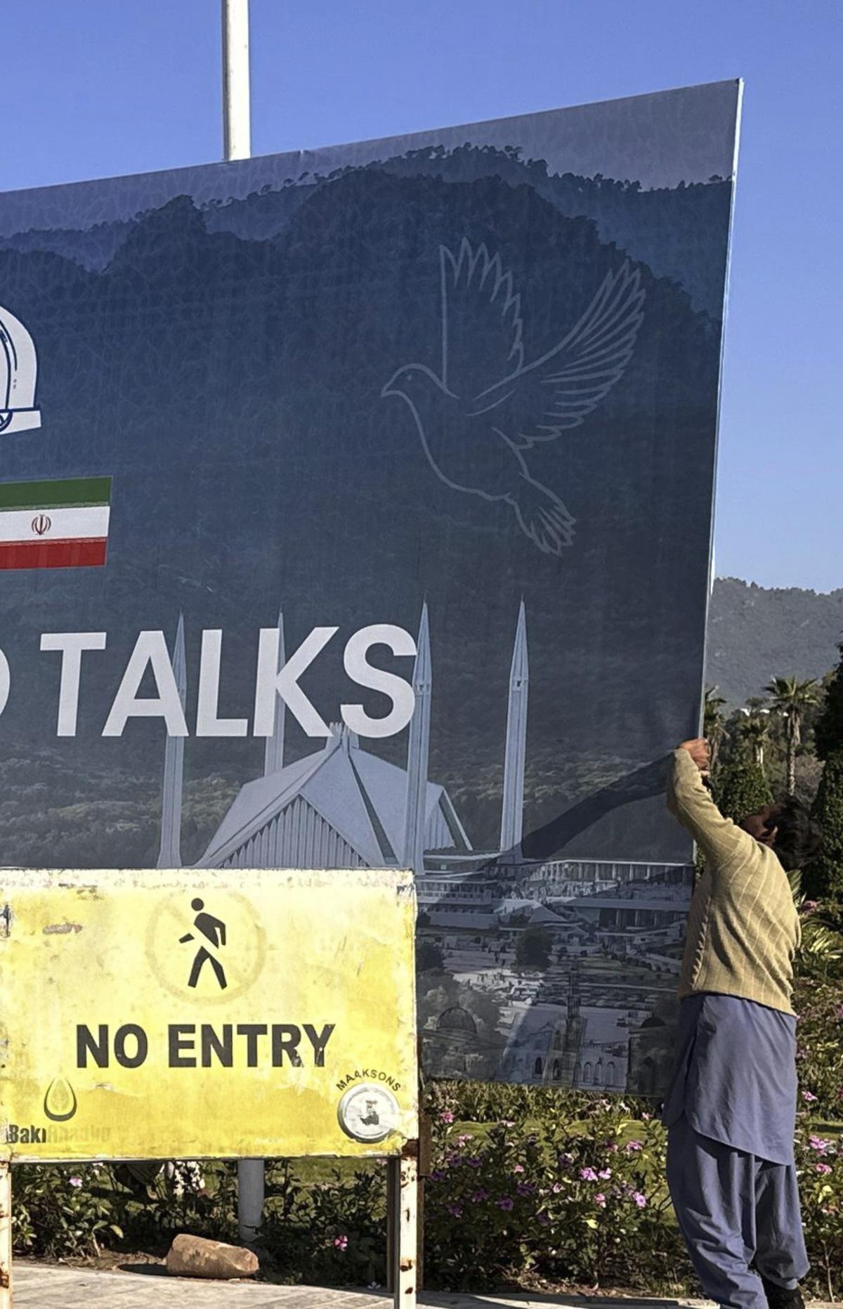 Un treballador retira un cartell que anunciava la reunió a Islamabad. | SOHAIL SHAHZAD / EFE
