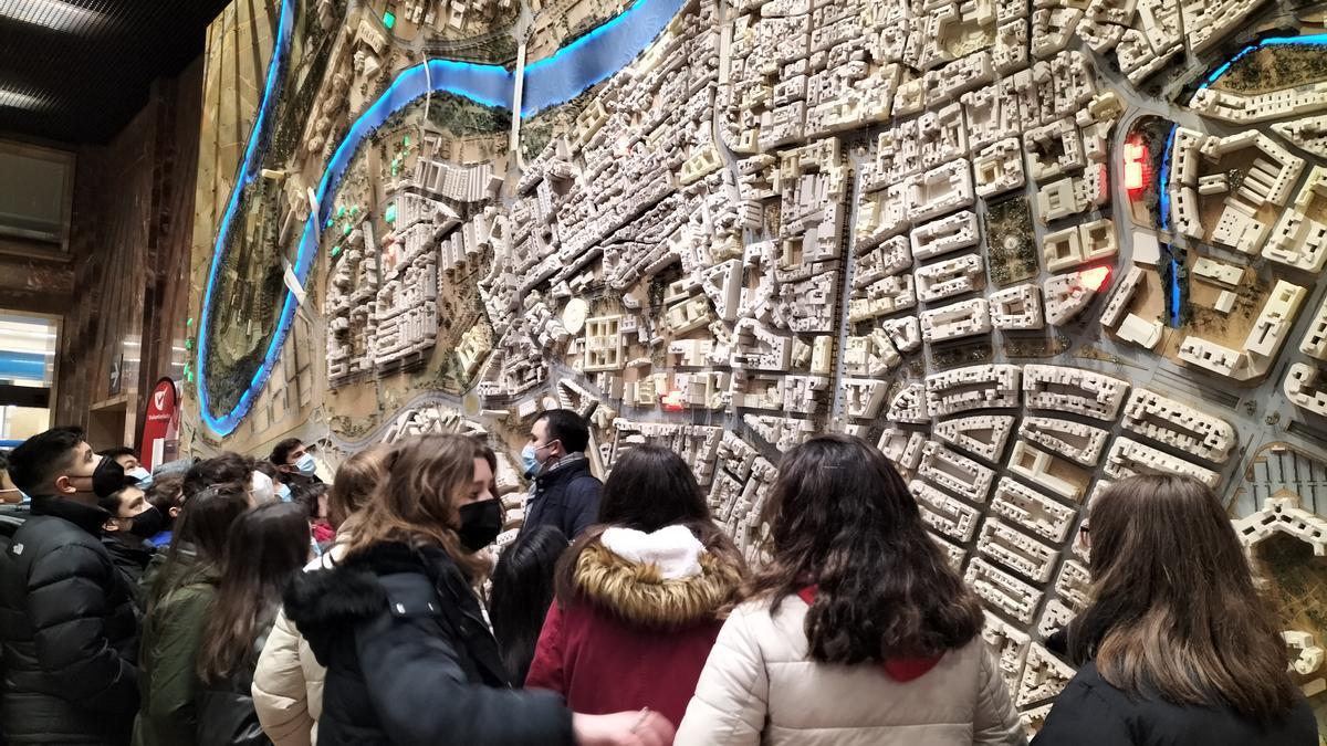 Los estudiantes contemplan la gran maqueta vertical de la ciudad de Zaragoza que hay en el ayuntamiento.