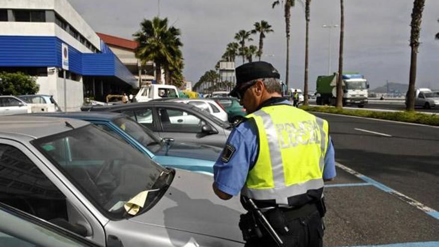 Un policía local pone una multa a un coche mal aparcado en la Avenida Marítima. i ANDRÉS CRUZ