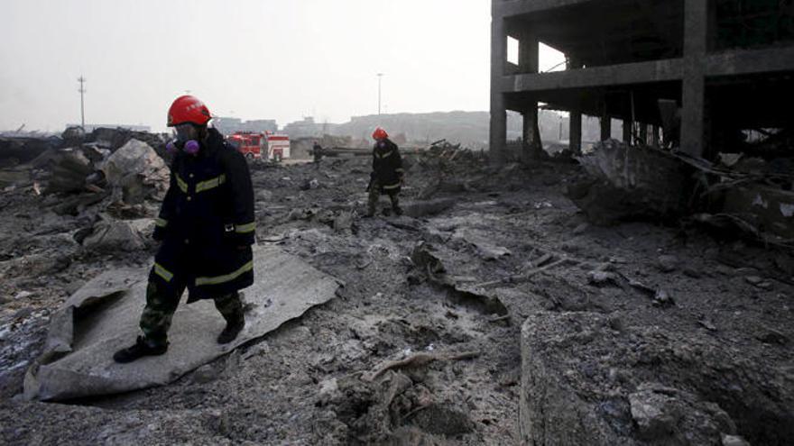 Dos bomberos inspeccionan, ayer, la zona próxima a una de las explosiones.