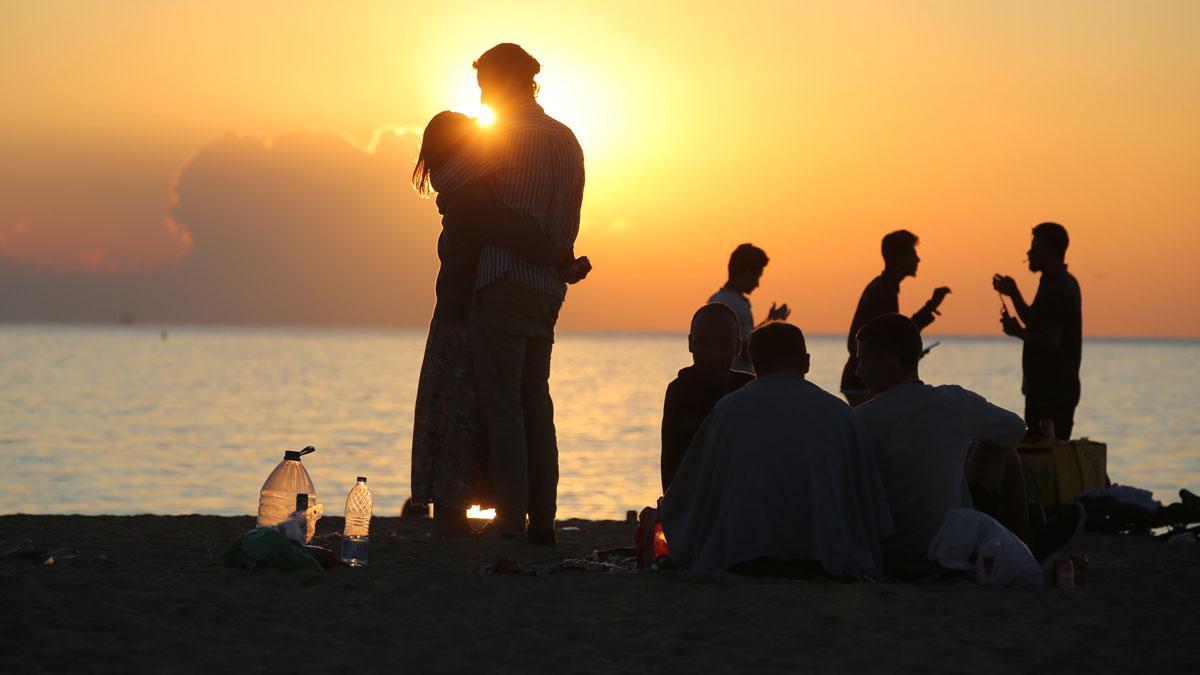 Dos jóvenes se abrazan, a primera hora de la mañana, en la Barceloneta, tras la verbena de Sant Joan