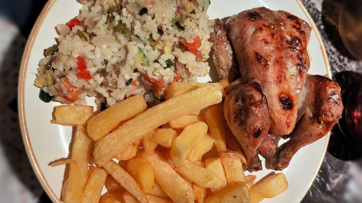 Un plato de picantón, arroz y patatas.