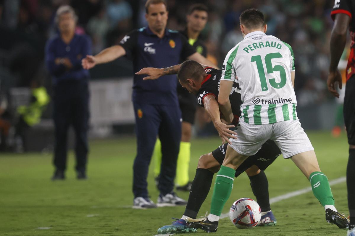 El defensa del Betis Romain Perraud lucha con Dani Rodríguez, del Mallorca, durante el partido de la sexta jornada de LaLiga que Real Betis y RCD Mallorca disputan hoy lunes en el estadio Benito Villamarín, en Sevilla.