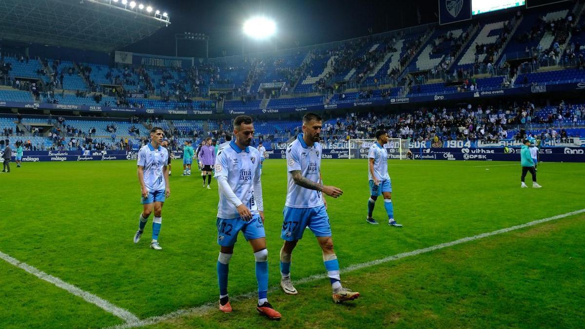 Los jugadores del Málaga abandonan cabizbajos el césped de La Rosaleda.
