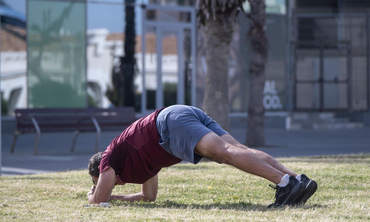 Barcelona. 22.04.2026. Sociedad. Un hombre hace deporte realizando ejercicios de estiramiento en una zona verde junto a la playa de la Barceloneta (para artículo sobre el aumento del ejercicio físico asociado a la longevidad). Fotografía de Jordi Cotrina