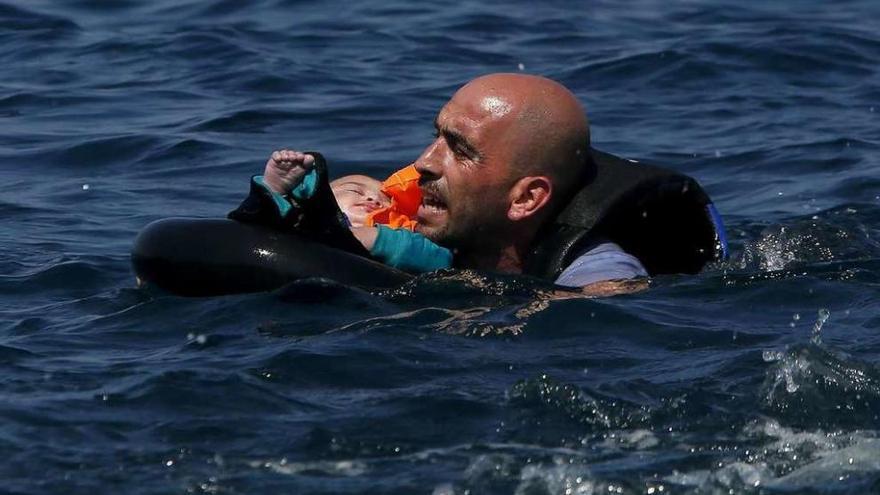 Un sirio sostiene a un bebé tras otro naufragio ocurrido en aguas de la isla de Lesbos. // Reuters