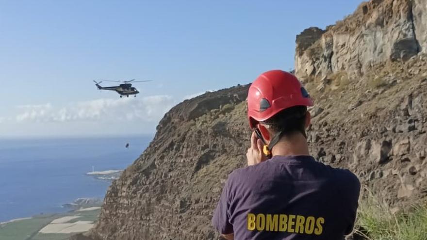 Un bombero de La Palma con el helicóptero de fondo durante el rescate.