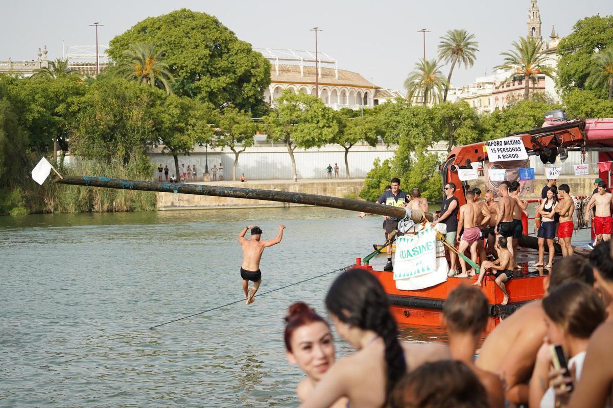 La 'cucaña', el juego centenario que regresa cada verano al río Guadalquivir por la Velá de Santa Ana en imágenes