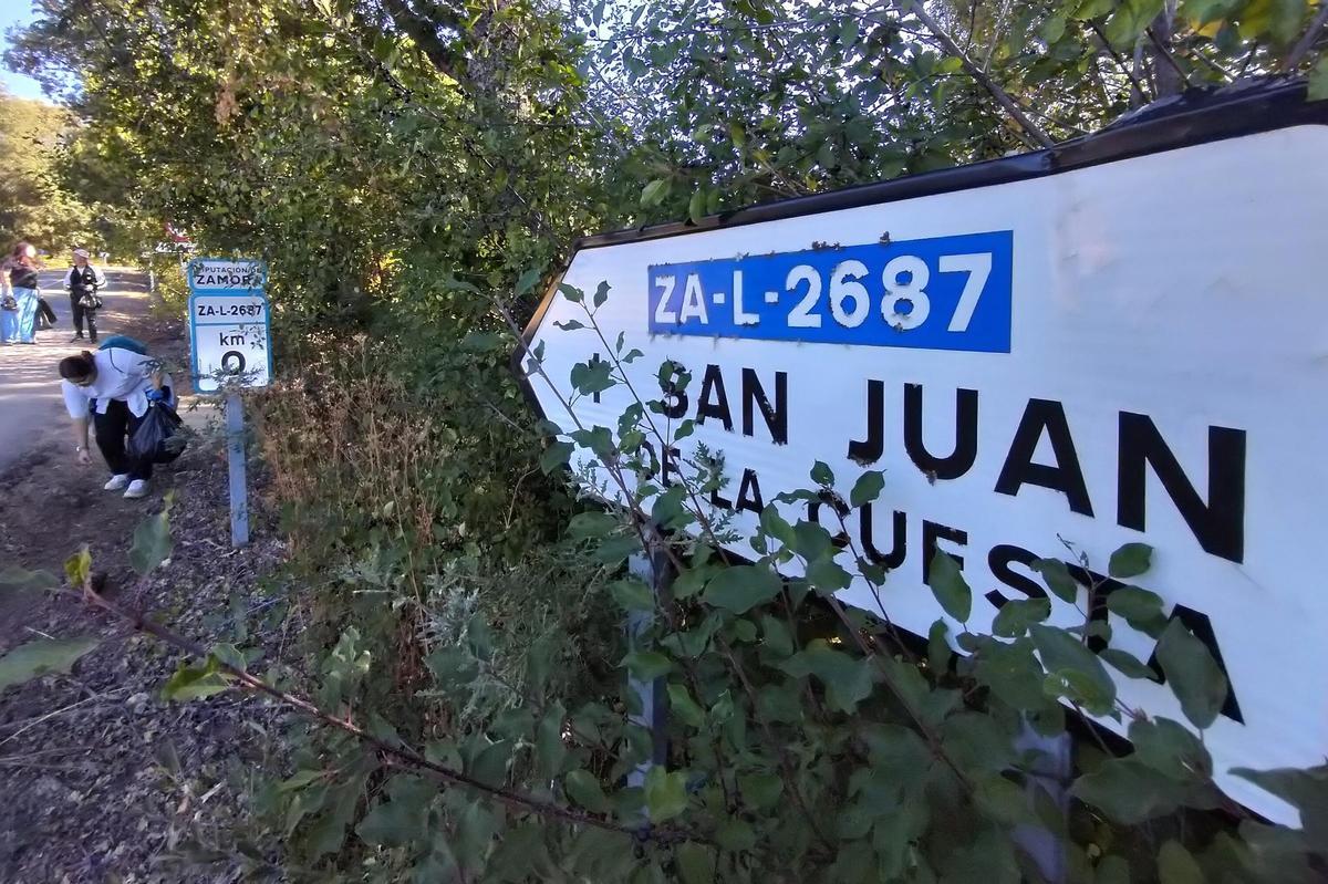 Vecinas retiran residuos en el entorno de la carretera de acceso al pueblo.