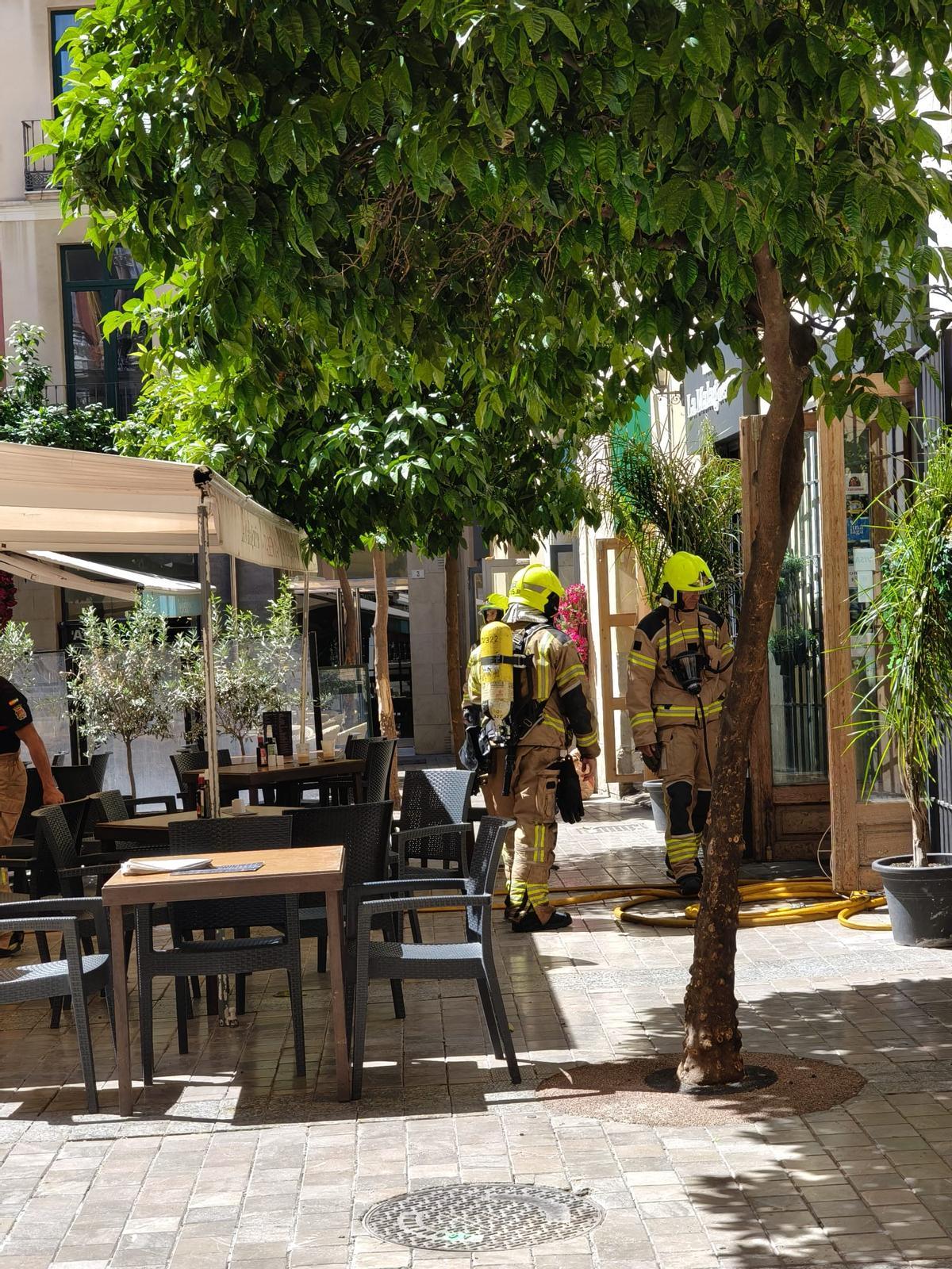 Bomberos en la entrada del restaurante La Malagueña, en la plaza del Obispo.
