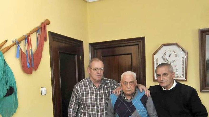 Modesto González, junto a sus hijos, con una gaita en la pared de la sala de estar de su casa, en Ujo.