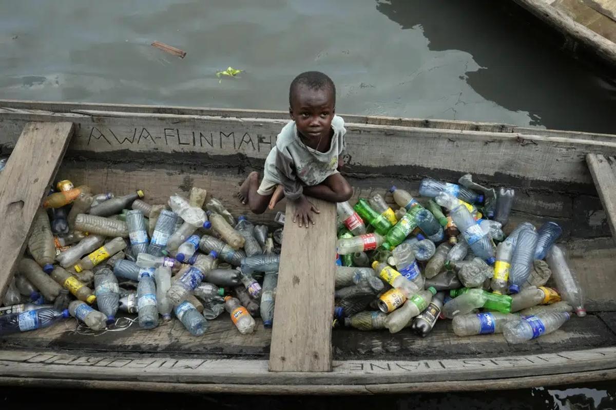 Un niño africano carga plásticos en una canoa