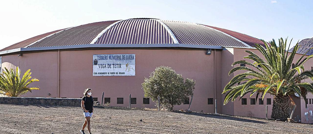 Una mujer camina por delante de la fachada del Terrero de Lucha Canaria ‘Vega de Tetir’.