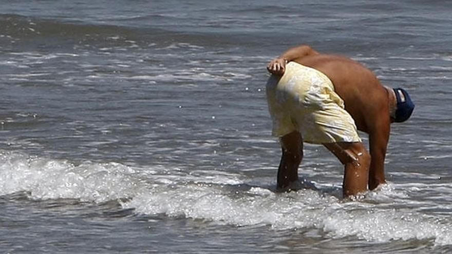 Un hombre busca tellinas en la playa.