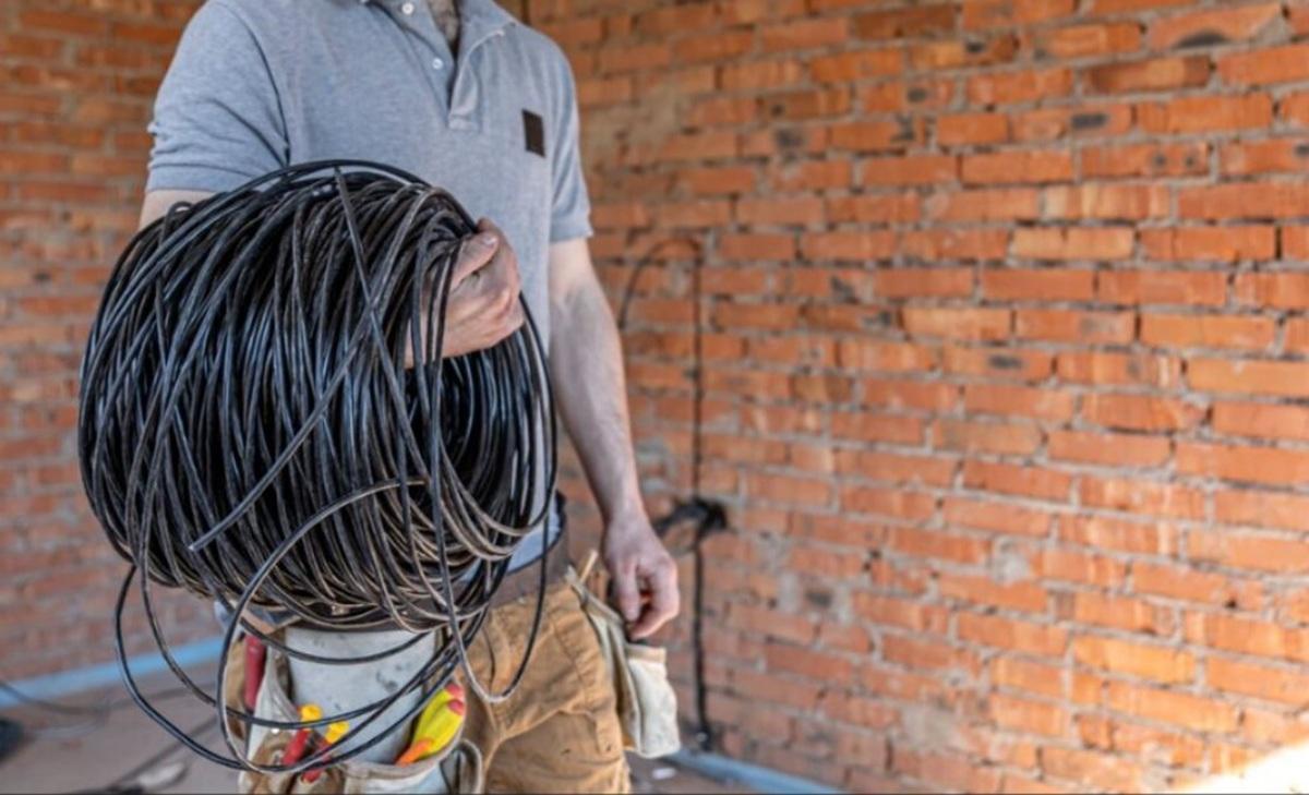Un operario con un hilo de cableado en la mano, en una foto de archivo.