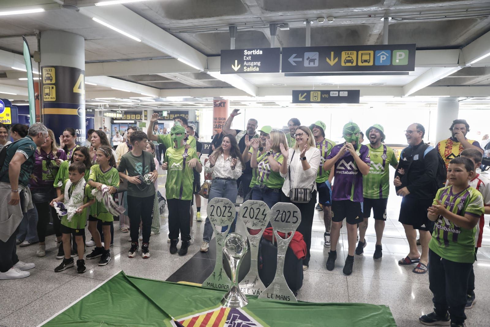 Medio centenar de aficionados reciben al Palma Futsal a su llegada a la isla tras conquistar la Champions