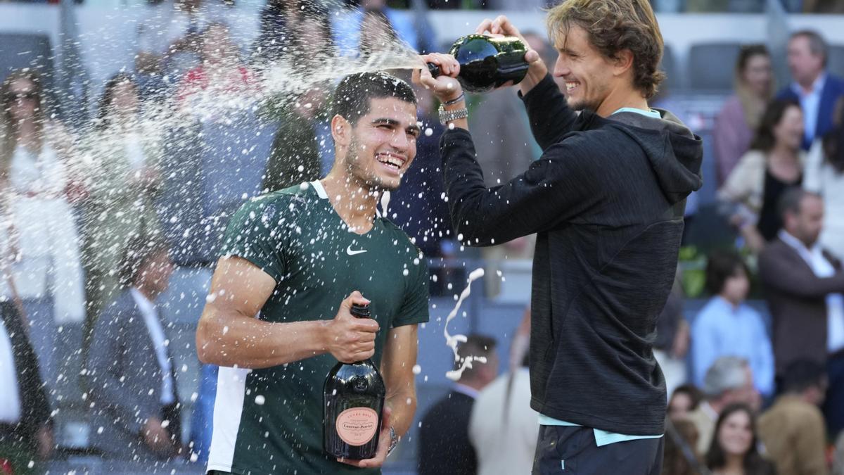 Alexander Zverev (r) besprüht Carlos Alcaraz nach dem Spiel mit Sekt.